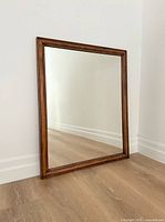 Full view of rectangular wood framed mirror leaning against wall