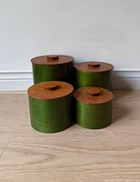 All four green canisters with teak lids grouped together