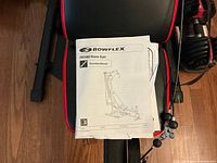 Manual on padded bench of Bowflex PR1000 showing assembly booklet