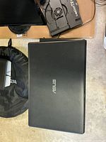 Top view of closed ASUS laptop with carrying sleeve and cooling stand visible