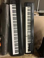 Two black M-Audio keyboards standing vertically side by side; left unit unlabelled, right unit labelled Keystation 88