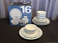 Dansk boxed 16-piece service and additional matching plates, bowls and mugs displayed