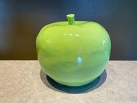 frontal view of large glossy green ceramic apple on countertop