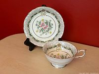 Teacup and saucer showing floral centre, EIIR crown monogram, scroll border and gold trim