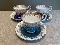 Front angled view showing all three coloured teacup and saucer sets