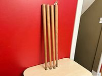 Four wooden legs standing upright against red wall
