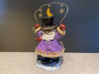 Front view of Santa figurine showing purple coat, wire arch, moon and stars