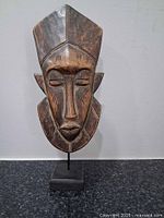 Front view of wooden Kpelie mask on stand