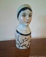 Front three-quarter view of ceramic lady head bust showing glaze, branch motif, and facial features