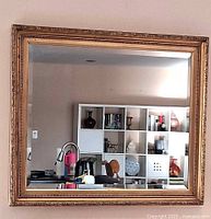 Front view of gold gilt rectangular wall mirror hanging indoors