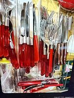 Full view of flatware set in tray showing red handles, forks, knives, spoons