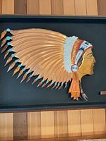 Full view of framed metal relief showing chief profile and headdress