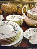 Stacks of salad/dessert plates, dinner plates, teapot, square serving dish with spoon visible