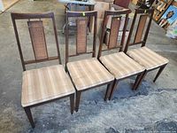 Front angled view of four walnut chairs showing frame design, cane backs, and seat upholstery