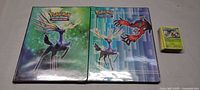 Two Pokémon binders and stack of loose cards