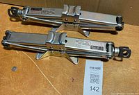 Two stainless steel scissor jacks on table
