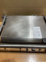 Closed Breville grill showing stainless steel lid and logo