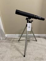 Telescope mounted on tripod standing on carpet