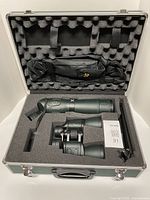 Foam-lined hard case open showing spotting scope, binoculars, tripod and accessory pouch
