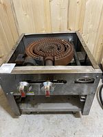 Front view of stainless steel gas burner showing cast-iron burner rings and hose