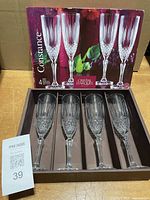 Open box displaying four crystal champagne flutes and outer sleeve with product image