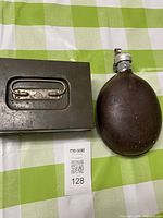 Metal box and Russian canteen side by side for scale