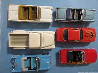 Top view showing six diecast toy cars: white convertible, light blue convertible, cream pickup, red Firebird, red convertible, blue convertible