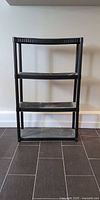 Front view of black plastic 4-shelf unit