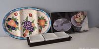 Group shot of oval platter, boxed glass plates, wood tray with three white dishes