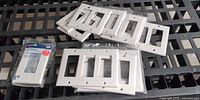 Sealed single-gang Leviton wall plate and assorted loose plates on rack