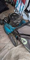 Left side view of Yardworks mower showing Honda engine, teal deck, large rear wheel and partial grass bag