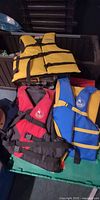 Three adult life jackets in yellow-black, red-black and blue-yellow