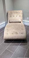 Front view of beige tufted chaise lounger with pillow