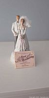 Front view of bride and groom music box figurine with information card