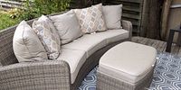 Curved wicker couch with cushions and ottoman on deck