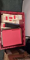bulk tote showing sealed Staples sticky note packs, red file folders, black binder