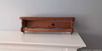 Front view of wooden wall shelf with dowel rod