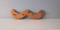 Front view of wooden snake hanger showing full length and four pegs