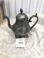 Full view of teapot on paper, showing overall form and leaf decoration