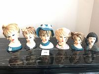 All six ceramic lady head vases lined on surface