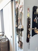 Wall display showing multiple necklaces and small evening bags suspended from hooks