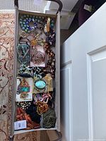 Overview of rectangular fabric bin filled with various costume jewelry pieces