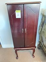 Front view of dark cherry Queen Anne-style jewelry armoire