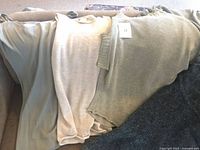 Four Sarah Pacini tops laid out: olive tank, beige tank, sage sweater, dark grey knit