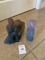 Both sculptures side by side on tile floor