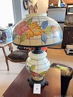 Full view of double-globe floral hurricane lamp on table