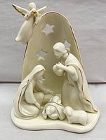 Front view of ivory porcelain nativity figurine with backdrop, angel, Holy Family and lambs