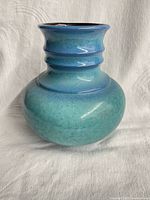Front view of turquoise ceramic vase showing rounded body and ribbed neck