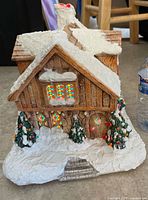 Front view of ceramic house showing lit windows and trees