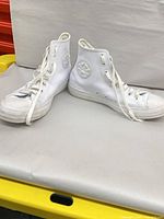 Pair of white Converse high-top sneakers on table